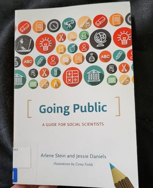 A barely-visible hand holds the book "Going Public: A Guide for Social Scientist". A library ISBN sticker is visible, wrapped around the bottom edge.